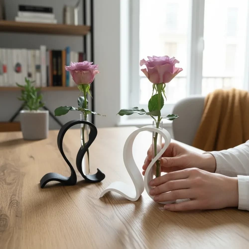 En sort og en hvid bølget holder side om side, hver med en lyserød rose i et reagensglas