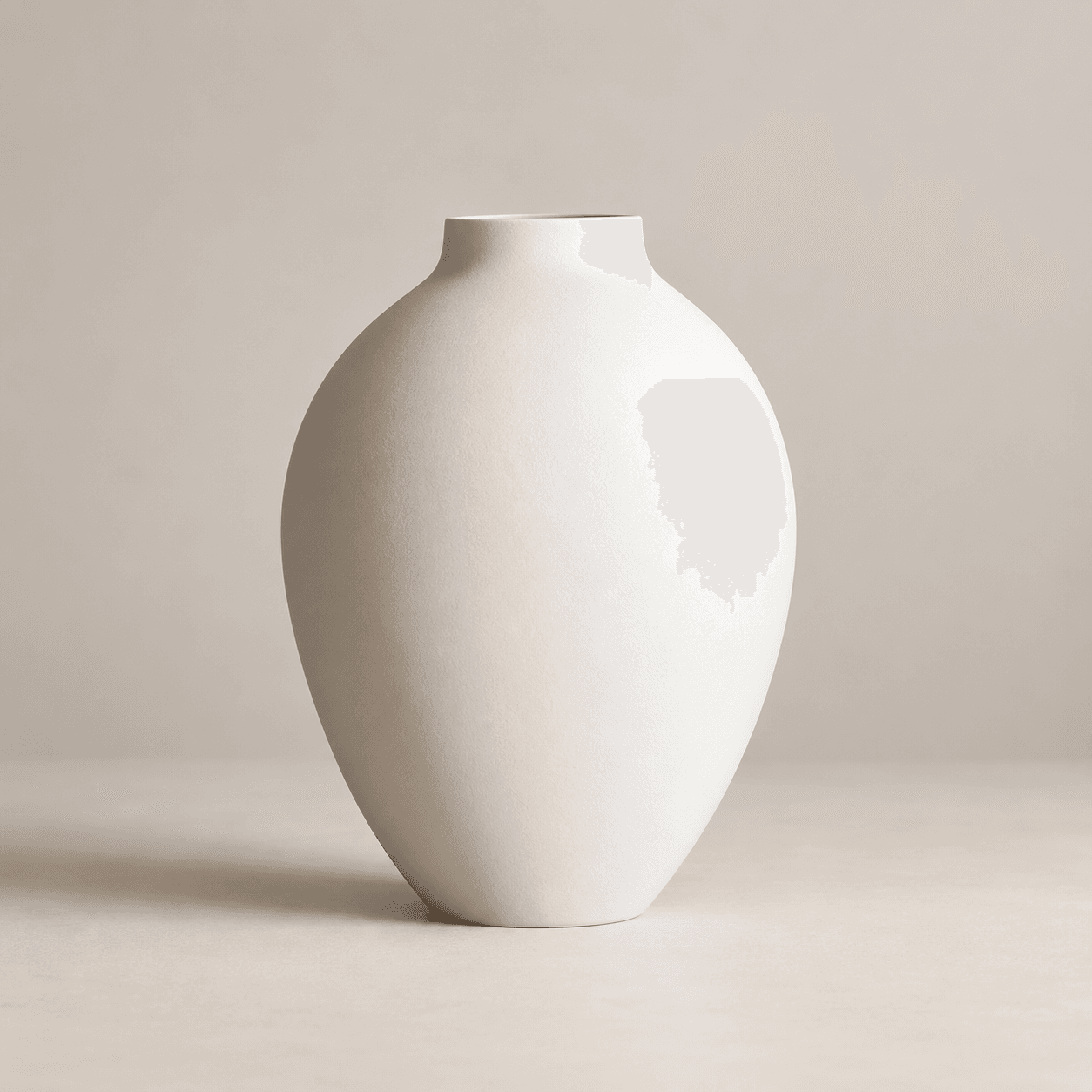 Hvid oval vase og en større mørk vase med tørret græs på et træbord