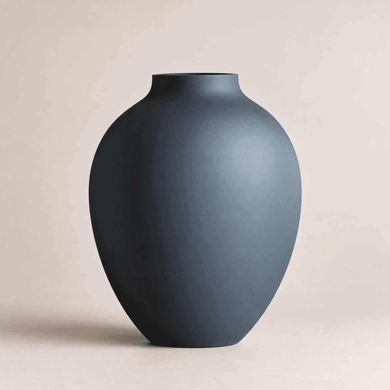 Grå oval vase og en større mørk vase med tørret græs på et træbord