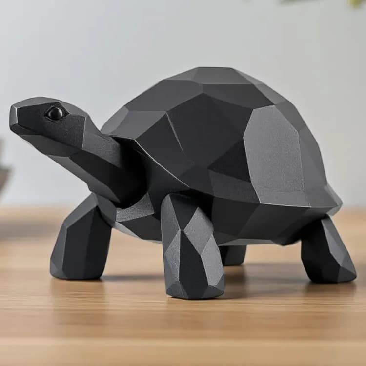 Sort skildpaddefigur i low poly på et lyst træbord med hovedet løftet