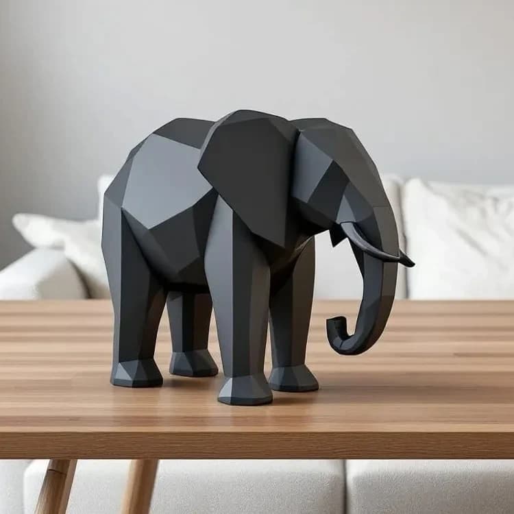 Sort low poly elefant på et lyst træbord foran en hvid sofa