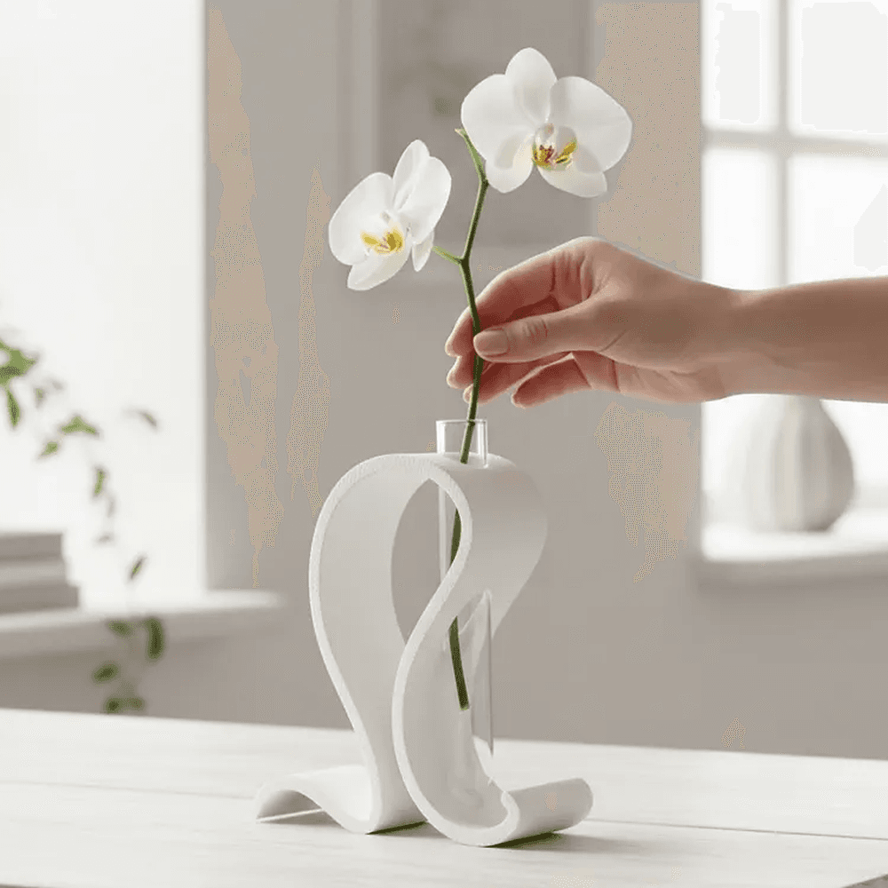 Hvid bølget reagensglas vase med en hvid orkidé i klart glas på et hvidt bord