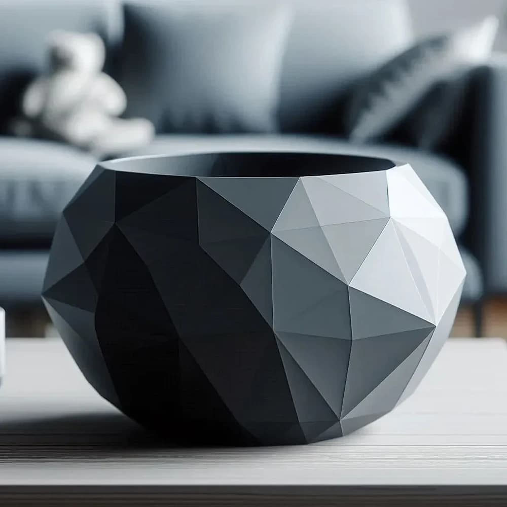 Grå low poly skål, hvis facetter går fra mørk til lysegrå i lyset, på et sofabord af lyst træ