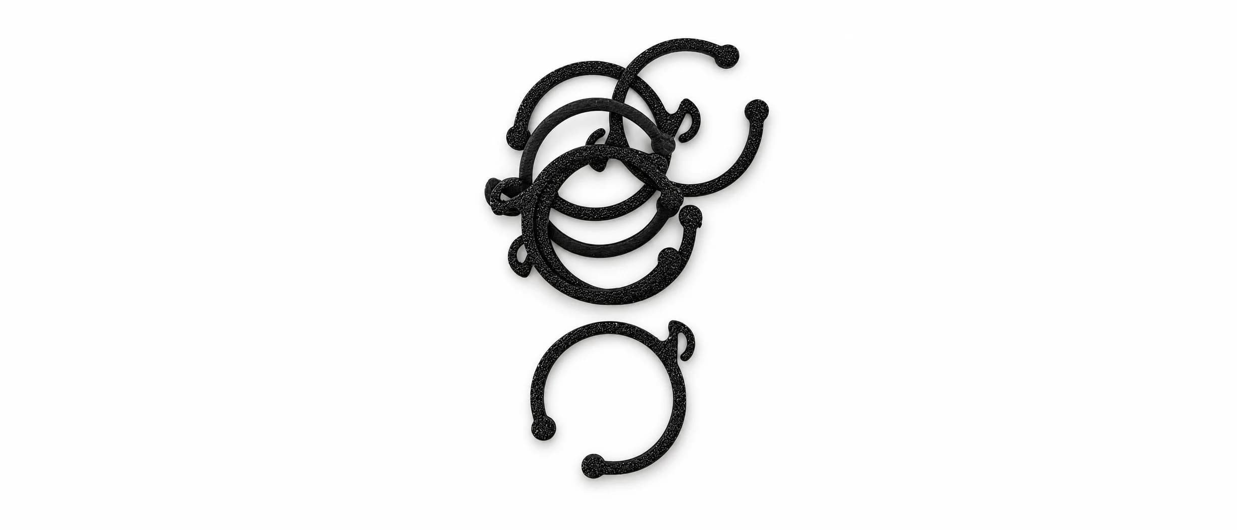 Bunke af sorte, åbne ringclips med en lille krog til ledningen, på hvid baggrund